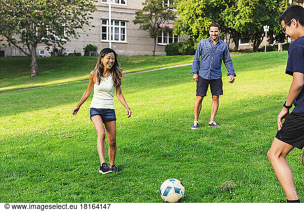 Happy family playing football on grass in lawn