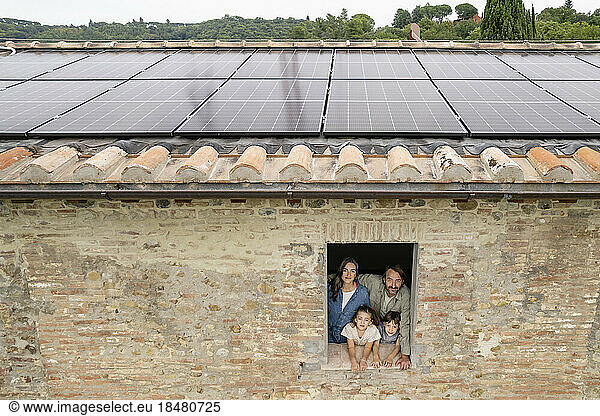 Happy family seen through window with solar panels on rooftop