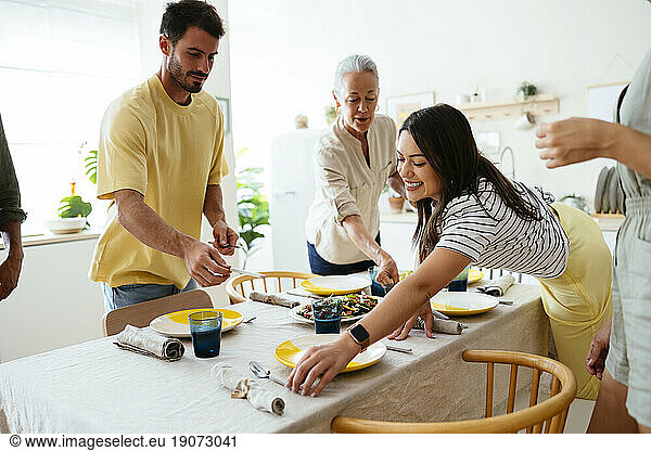 Happy family setting table in kitchen