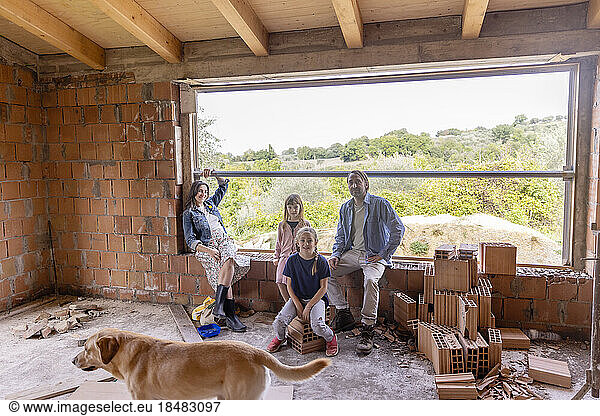 Happy family sitting in window sill with dog at home