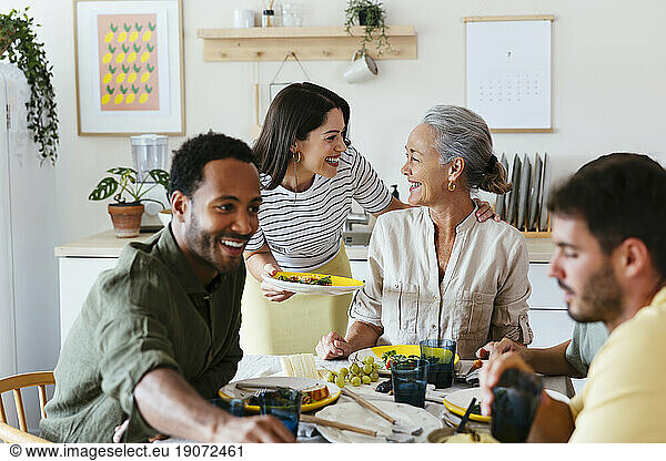 Happy family spending leisure time having lunch at dining table in kitchen
