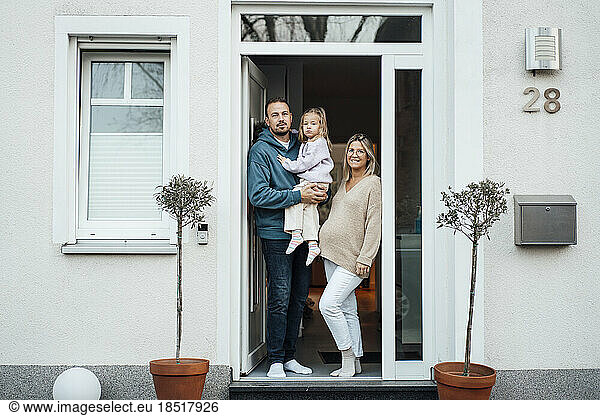 Happy family standing at front door