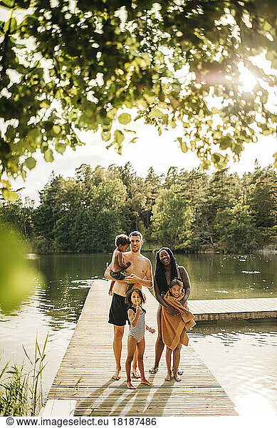 Happy family standing together on jetty at lake during vacation