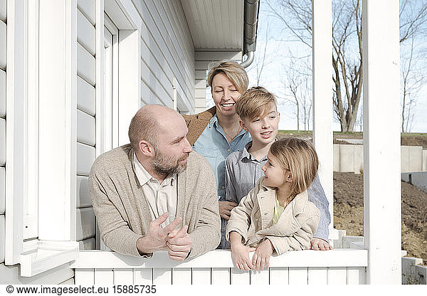 Happy family talking on porch of their house