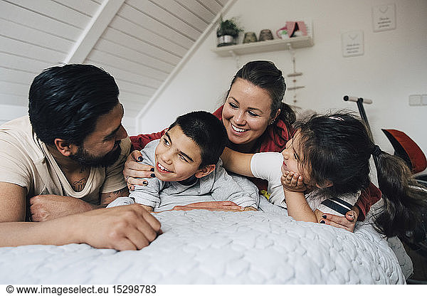 Happy family talking while lying on bed at home