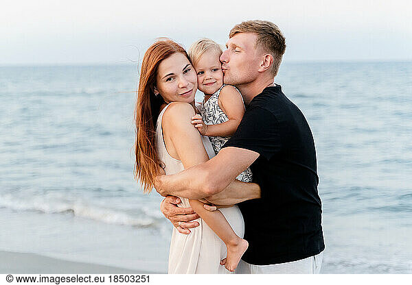 Happy family with baby hugging on the beach on vacation