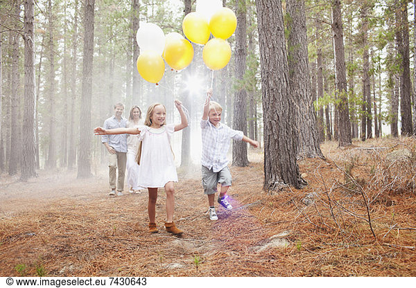 Happy family with balloons in woods