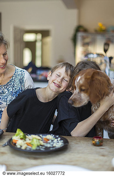 Happy family with dog eating lunch at dining table