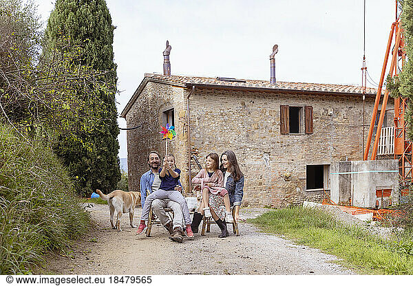 Happy family with dog sitting in front of house