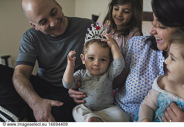 Happy family with mom  dad  2 girls and baby wearing costume crown