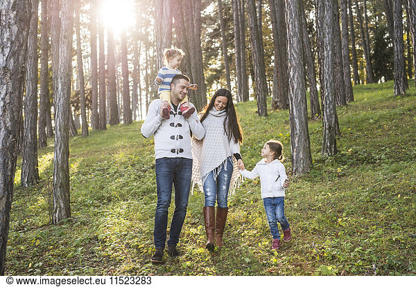 Happy family with two girls walking in forest