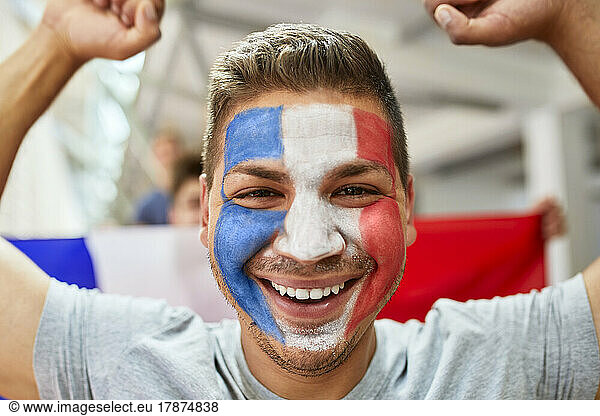 Happy fan with French Flag painted on face at stadium