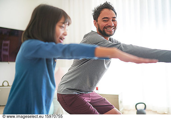 Happy father and daughter exercising in living room