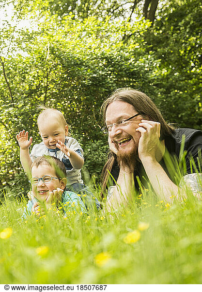 Happy father and his two sons lying in the garden
