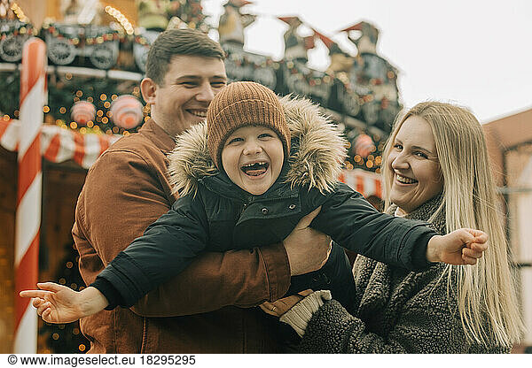 Happy father and mother having fun with son at Christmas market