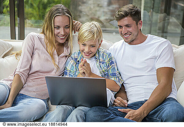 Happy father and mother with son using laptop at home