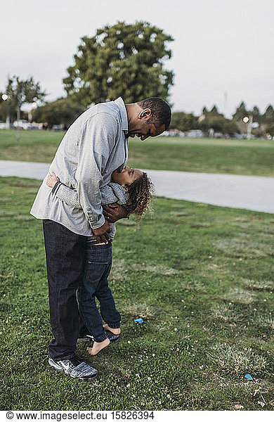 Happy father and son embracing outside at park at dusk