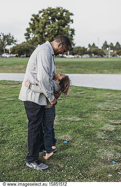 Happy father and son embracing outside at park at dusk