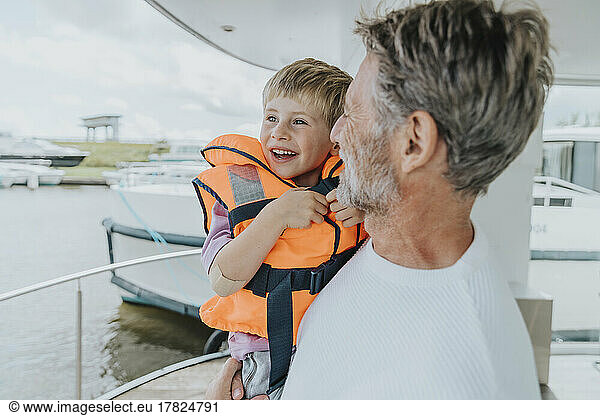 Happy father carrying son in balcony at houseboat