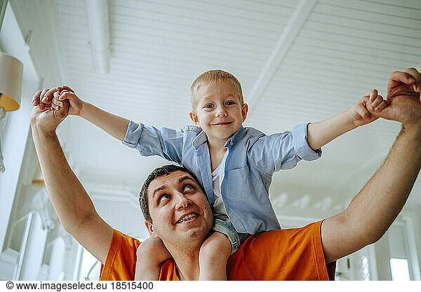 Happy father carrying son on shoulders at home