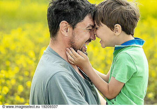 Happy father embracing son at field