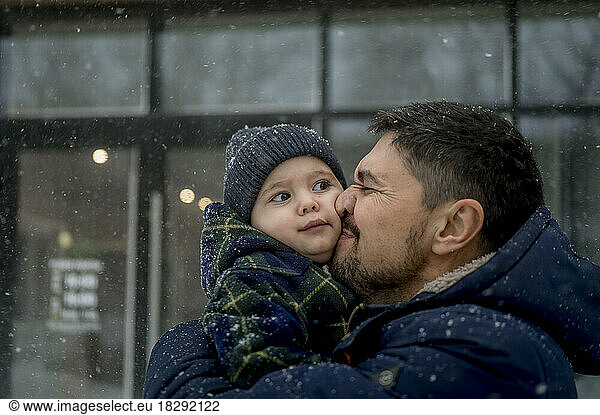 Happy father embracing son in snowfall