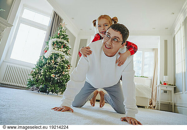 Happy father giving piggyback ride to daughter on carpet at home