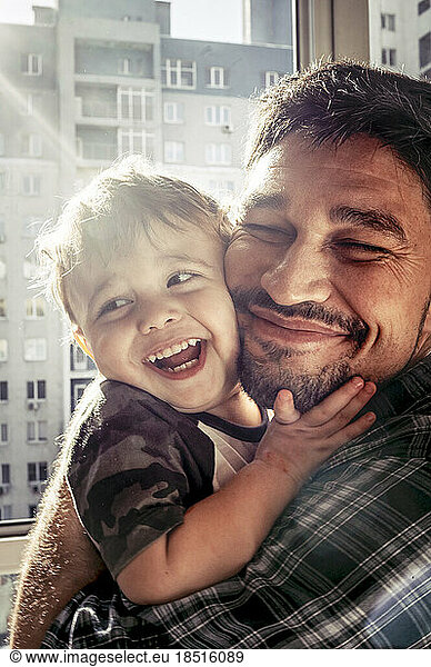Happy father having fun with son on sunny day at home