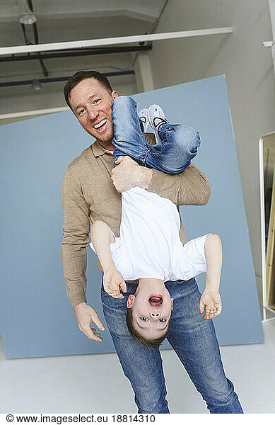 Happy father holding son in upside down position
