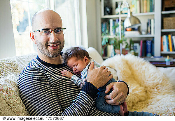 Happy father holds his newborn son at home.