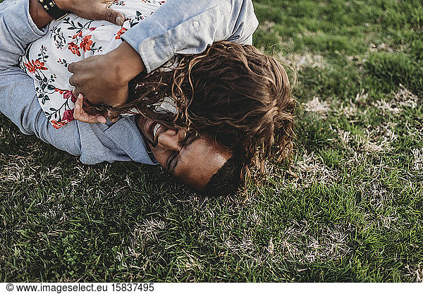 Happy father laying on grass playing with young daughter