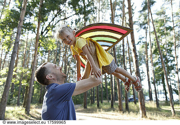 Happy father lifting up cute daughter in forest