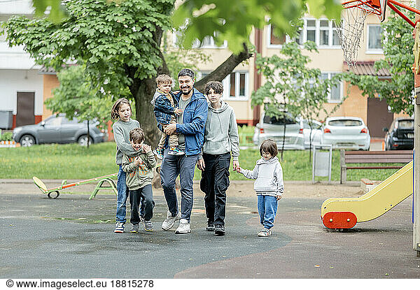 Happy father walking with children on playground