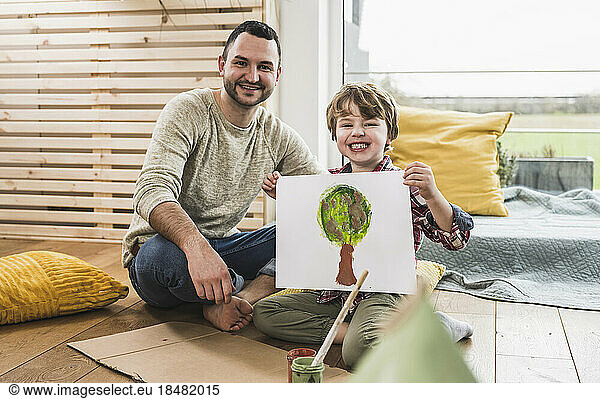 Happy father with son showing tree painting at home
