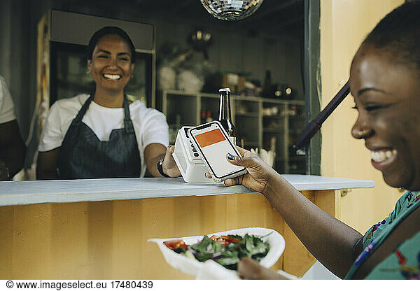 Happy female customer doing contactless payment at food truck