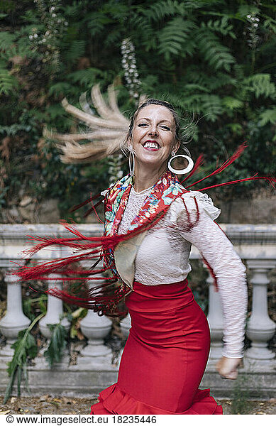 Happy female dancer dancing in front of trees