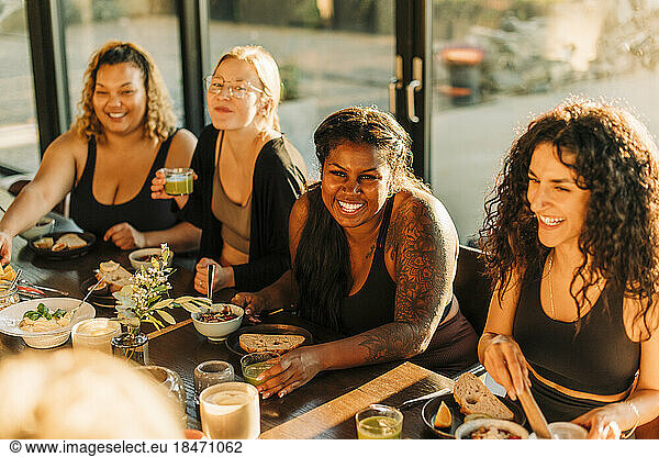 Happy female friends enjoying breakfast together at retreat center