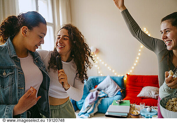 Happy female friends enjoying while singing together at home