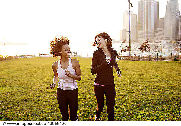 Happy female friends jogging at park in city