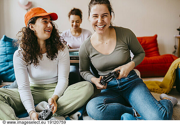 Happy female friends playing video game at home
