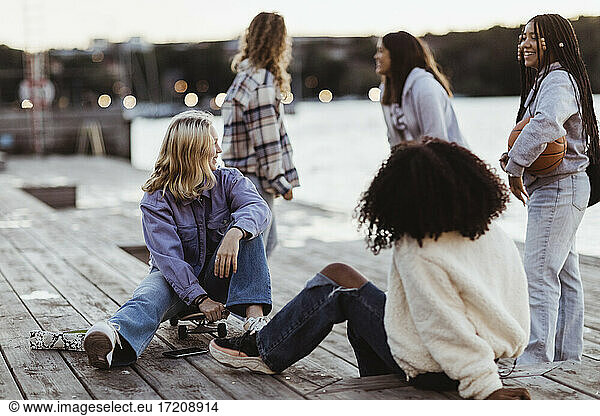 Happy female friends spending leisure time on pier during sunset