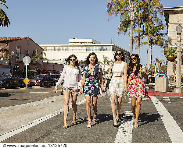 Happy female friends walking on city street