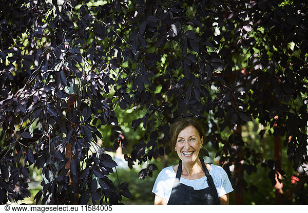 Happy female gardener surrounded by branches in yard