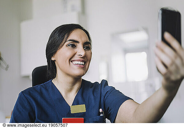 Happy female nurse doing video call through smart phone at hospital