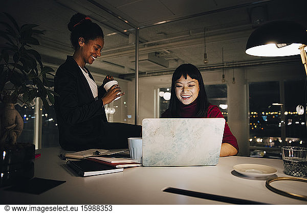 Happy female professionals working late during meeting in office
