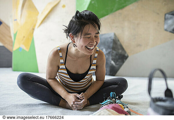 Happy female rock climber stretching in climbing gym