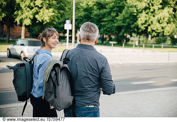Happy female talking to mature man while walking in city