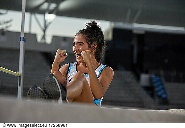 Happy female track and field athlete celebrating high jump