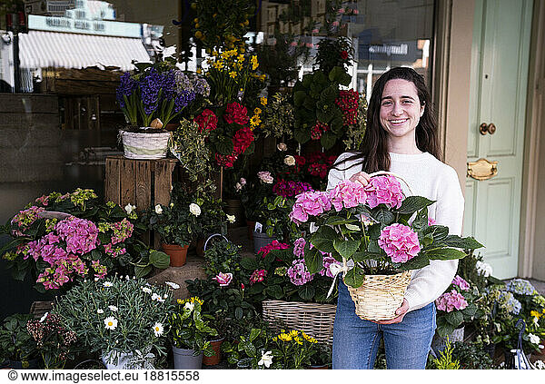 Happy florist standing with bouquet of flowers at shop