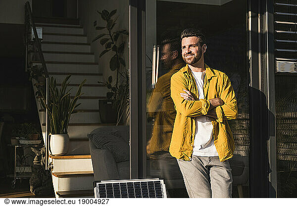Happy freelancer with arms crossed leaning on glass